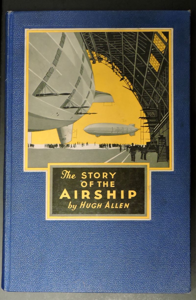 Colour pictorial cover of book showing the tail of an airship inside a huge hangar with floating airship outside